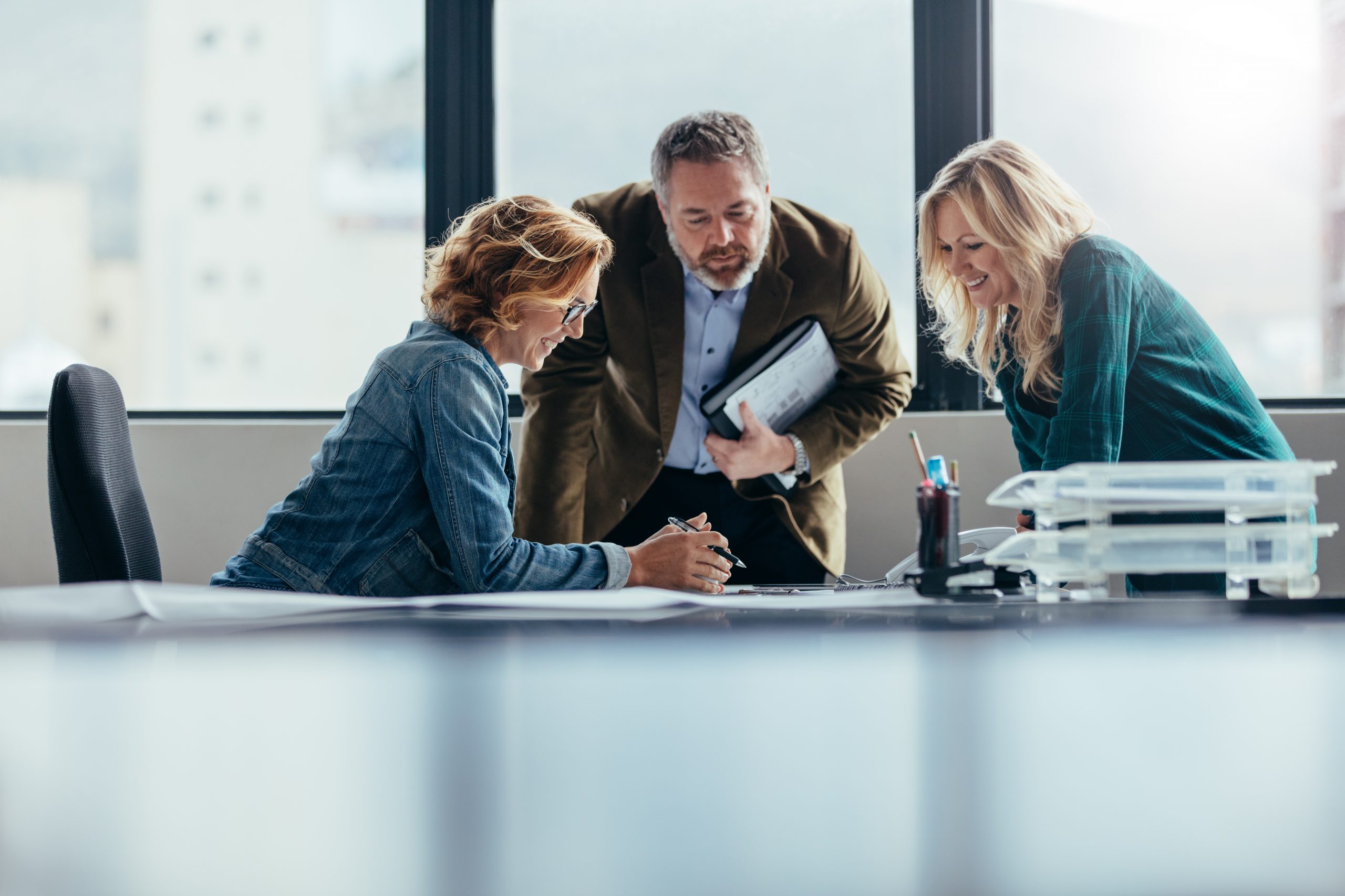 Drie collega's aan een bureau verbeelden de samenwerking tussen Axians, TransitieProfs en Hewlett Packard Enterprise